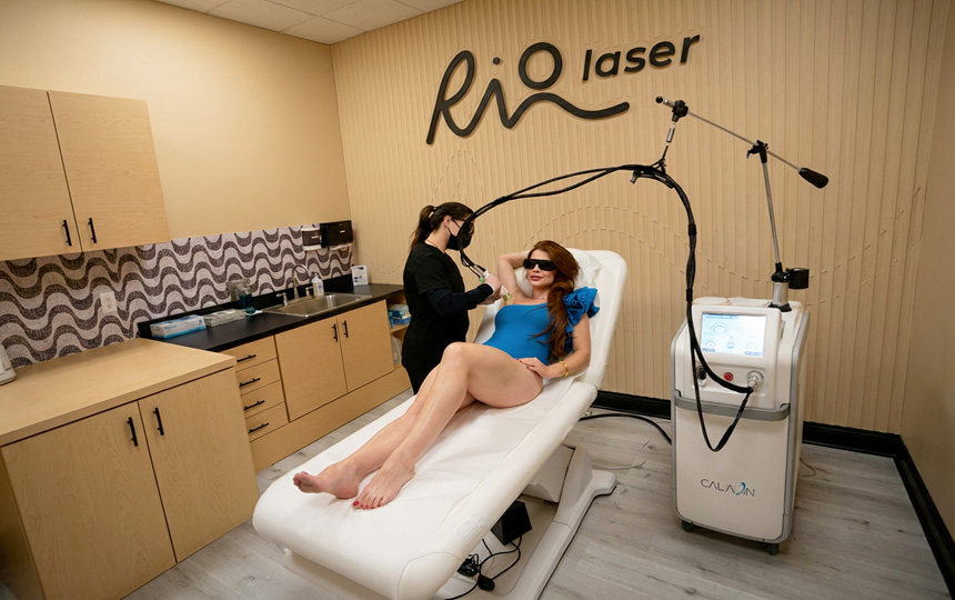Client receiving laser hair removal treatment at Riolaser Orlando, lying on a treatment bed while technician applies laser to underarms. Comfortable, professional clinic environment.